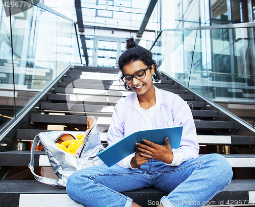 Image of young cute indian girl at university building sitting on stairs 