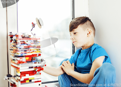 Image of little cute preschooler boy playing lego toys at home happy smil