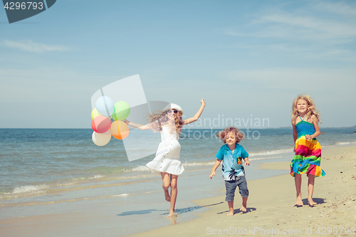 Image of Three happy children with balloons  dancing on the beach