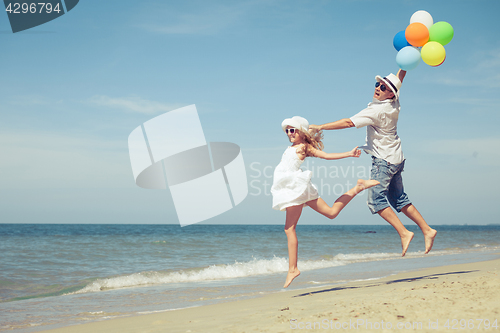 Image of Father and daughter with balloons playing on the beach at the da