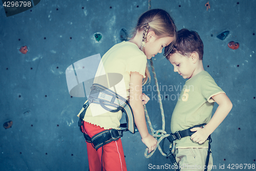 Image of brother and sister standing near a rock wall for climbing 