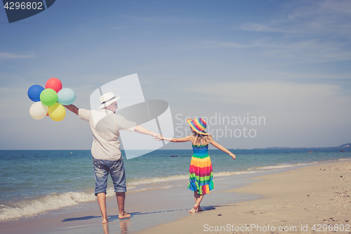 Image of Father and daughter with balloons playing on the beach at the da