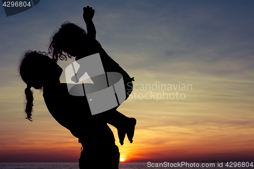 Image of Mother and son playing on the beach at the sunset time.