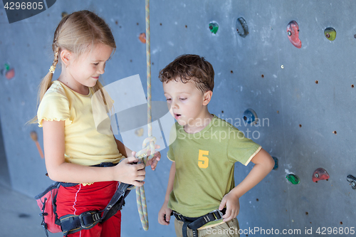 Image of brother and sister standing near a rock wall for climbing