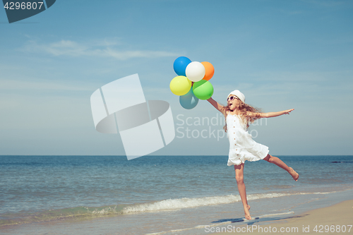 Image of Teen girl with balloons jumping on the beach