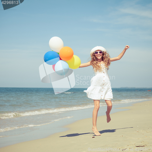 Image of Teen girl with balloons jumping on the beach