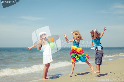 Image of Three happy children with balloons  dancing on the beach