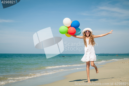 Image of Teen girl with balloons jumping on the beach