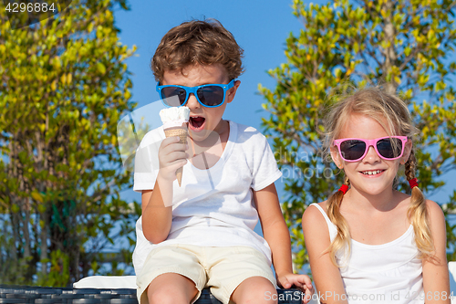 Image of Three happy children eating ice cream near swimming pool at the 