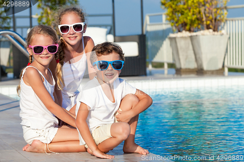 Image of Three happy children playing on the swimming pool at the day tim