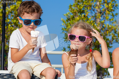 Image of Three happy children eating ice cream near swimming pool at the 