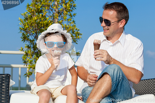 Image of Father and son relaxing near a swimming pool at the day time.