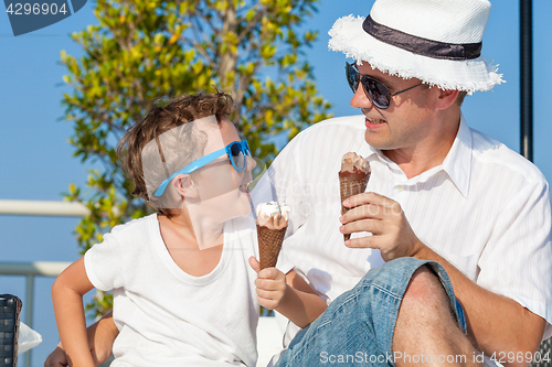 Image of Father and son relaxing near a swimming pool at the day time. 