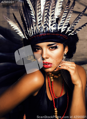 Image of young pretty woman with make up like North American indian, feather in hair, fashion halloween concept creative