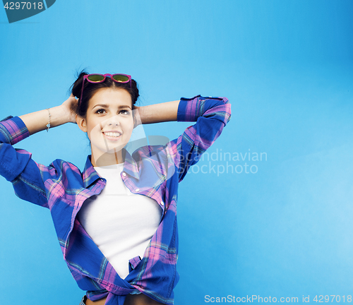 Image of young pretty teenage modern hipster girl posing emotional happy smiling on blue background, lifestyle people concept 