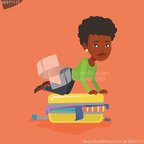 Image of Young woman trying to close suitcase.