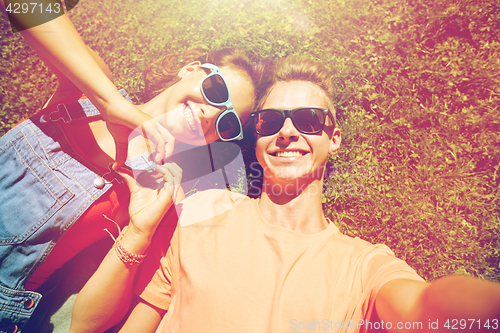 Image of happy teenage couple taking selfie on summer grass