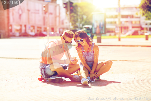 Image of couple with skateboards and smartphone in city