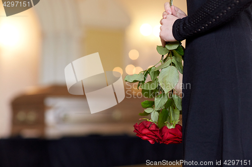 Image of close up of woman with roses and coffin at funeral