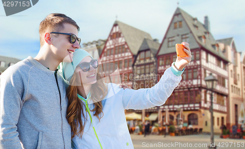 Image of smiling couple with smartphone taking selfie