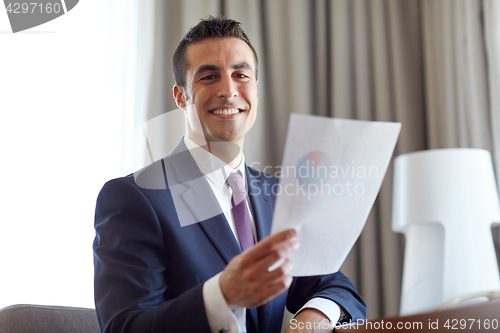 Image of businessman with papers working at hotel room