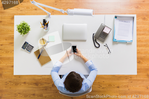 Image of businesswoman with smartphone working at office