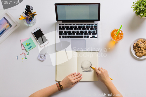 Image of woman hands drawing in notebook at home office