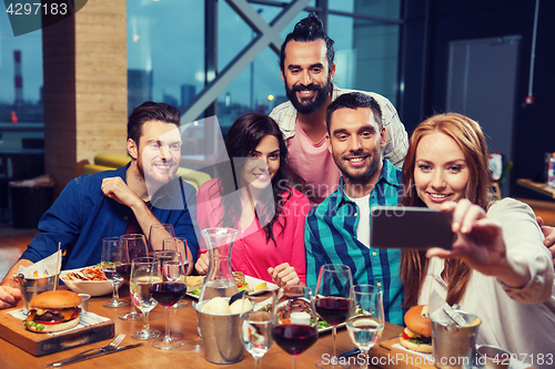 Image of friends taking selfie by smartphone at restaurant