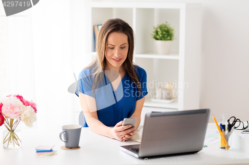 Image of woman with smartphone and laptop at office