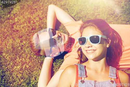 Image of happy teenage couple lying on grass at summer