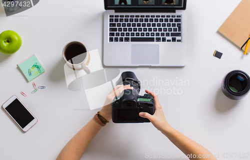 Image of woman hands with camera working on laptop at table