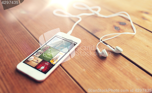 Image of close up of smartphone and earphones on wood