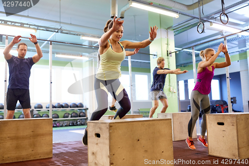 Image of group of people doing box jumps exercise in gym