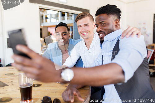 Image of friends taking selfie and drinking beer at bar