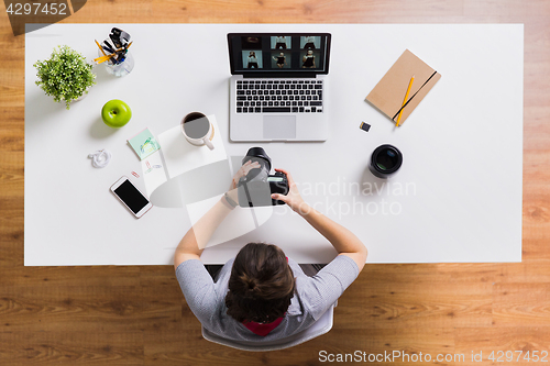 Image of woman with camera and laptop at office table