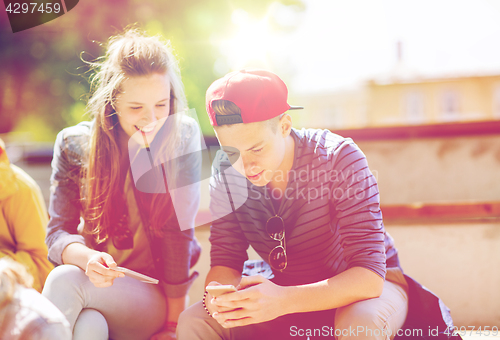 Image of happy teenage friends with smartphones outdoors