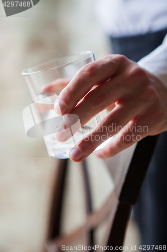 Image of Close up man holding glass of drinking water