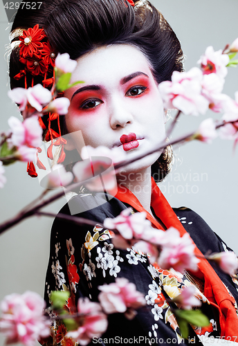 Image of young pretty geisha in kimono with sakura and red decoration design on white background