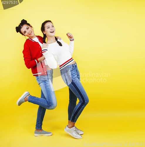 Image of lifestyle people concept: two pretty young school teenage girls having fun happy smiling on yellow background 