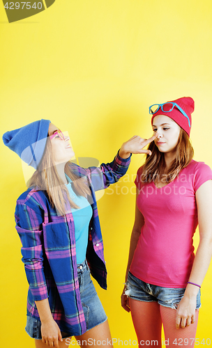 Image of lifestyle people concept: two pretty young school teenage girls having fun happy smiling on yellow background 