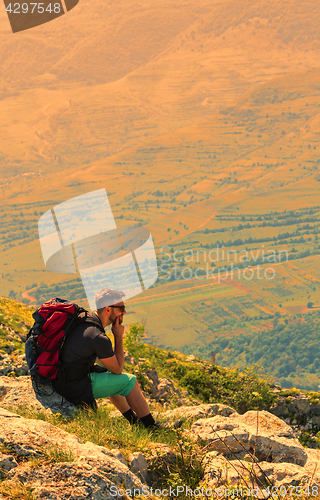 Image of Hiker Resting on Rocks in Mountains