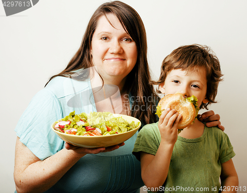 Image of mature woman holding salad and little cute boy with hamburger te