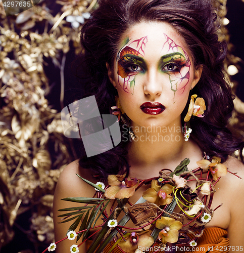 Image of beauty woman with face art and jewelry from flowers orchids clos