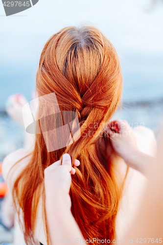 Image of Woman braiding girl on beach