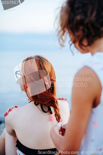 Image of Woman braiding girl on beach