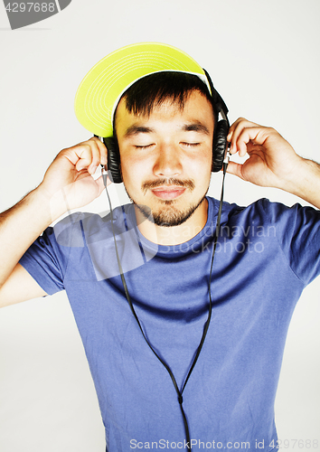 Image of young asian man in hat and headphones listening music on white b