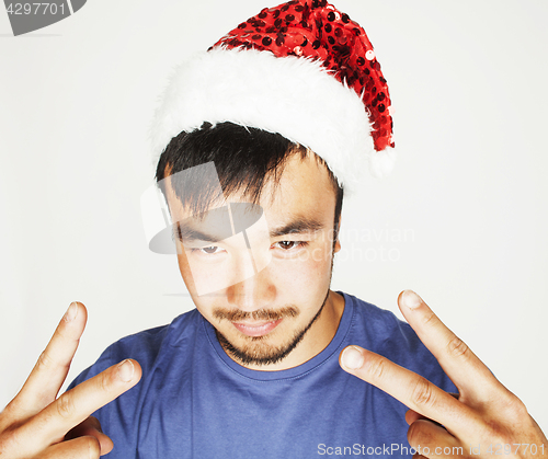 Image of funy exotical asian Santa claus in new years red hat smiling