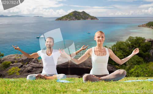 Image of happy couple doing yoga and meditating outdoors