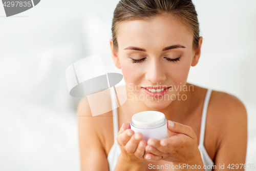 Image of close up of happy woman holding and smelling cream