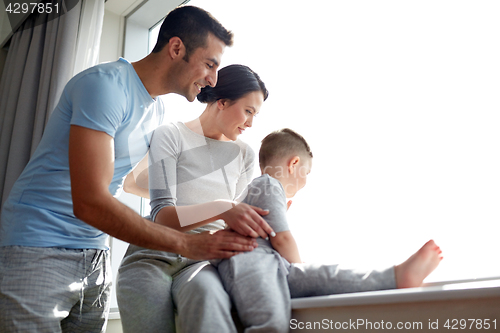Image of happy family looking through window at home